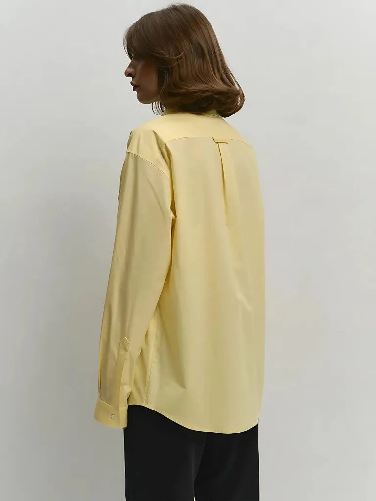 Person wearing a light yellow shirt against a plain background