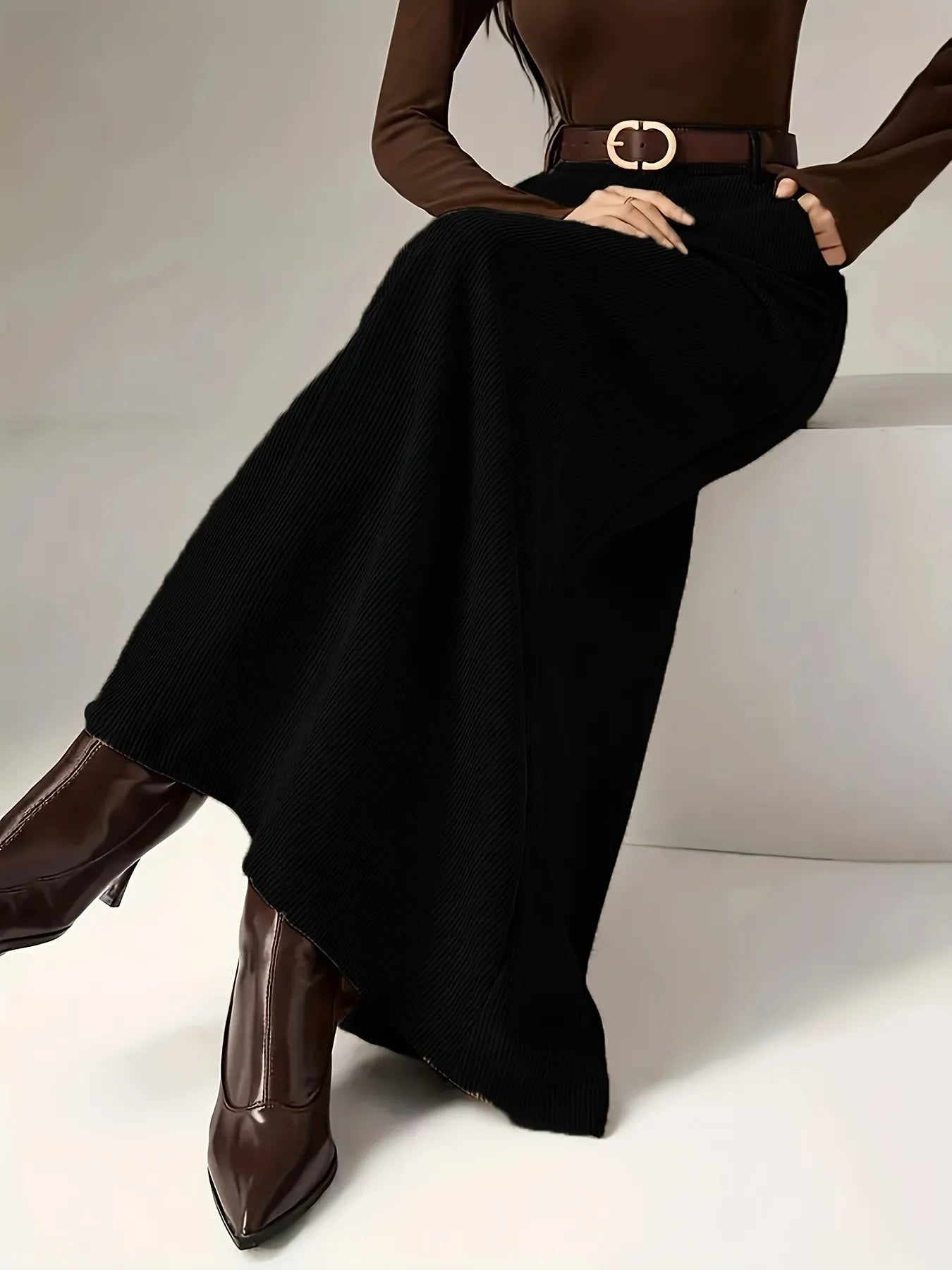 Person wearing a brown top, black skirt, and brown shoes on a white background