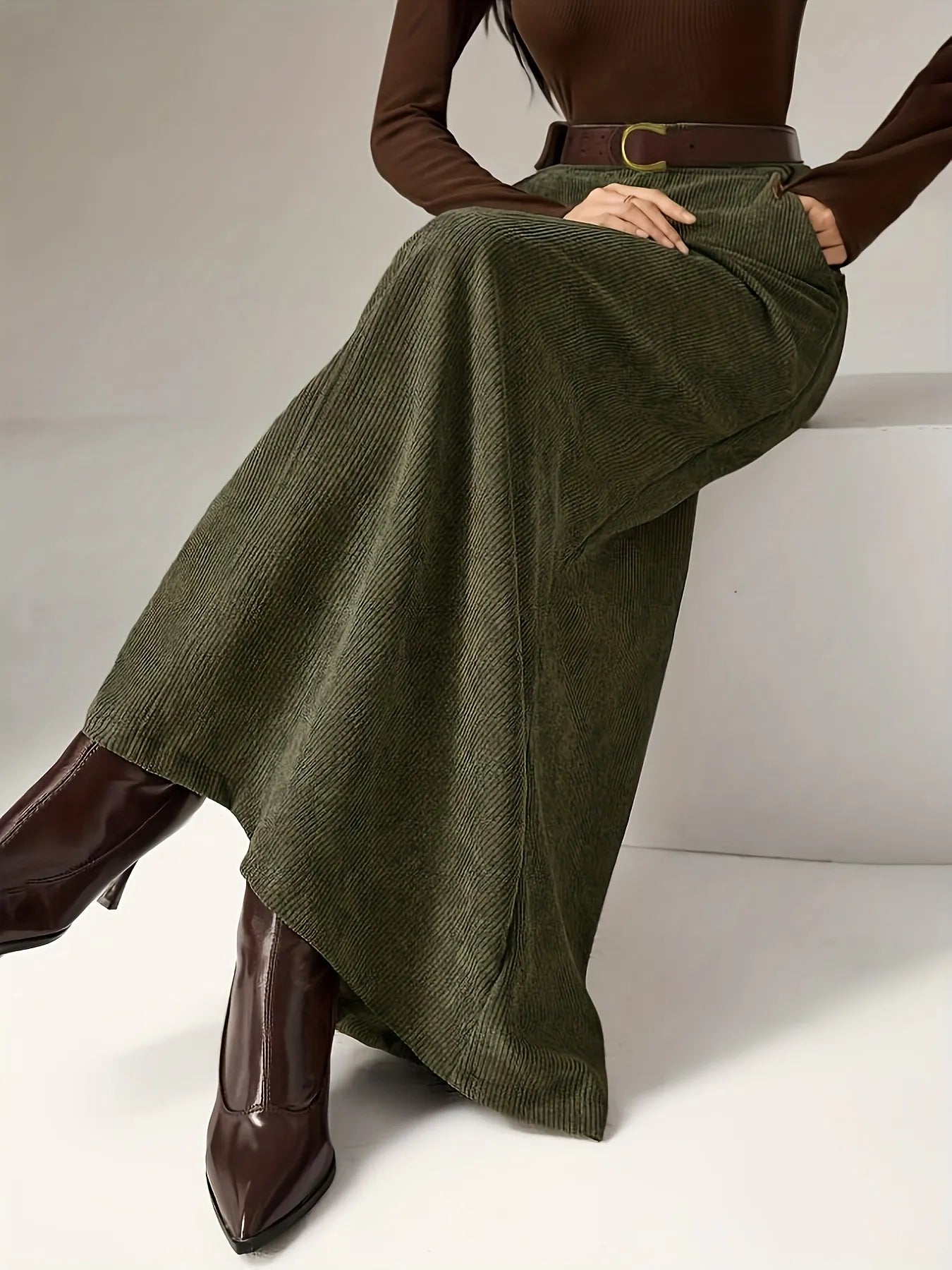 Person wearing a brown top, green skirt, and brown shoes on a white background