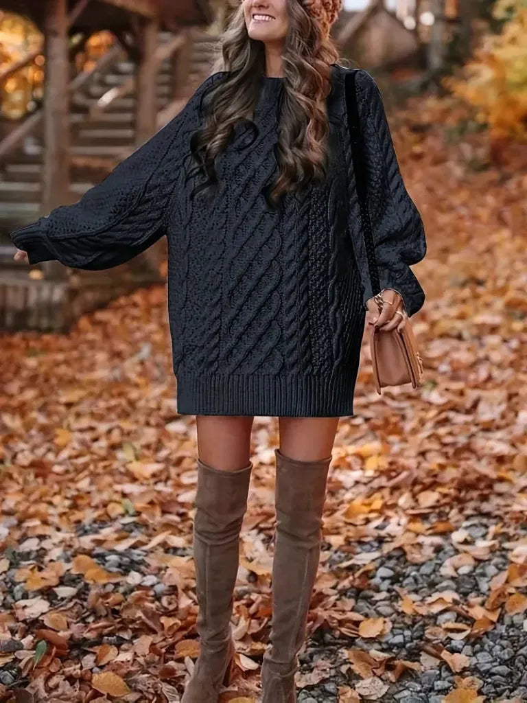 Woman wearing a dark blue cable knit sweater and brown knee-high boots in an autumn setting.