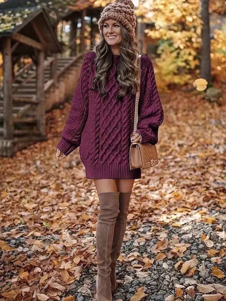 Woman in a purple sweater and brown over-the-knee boots standing in an autumn setting.