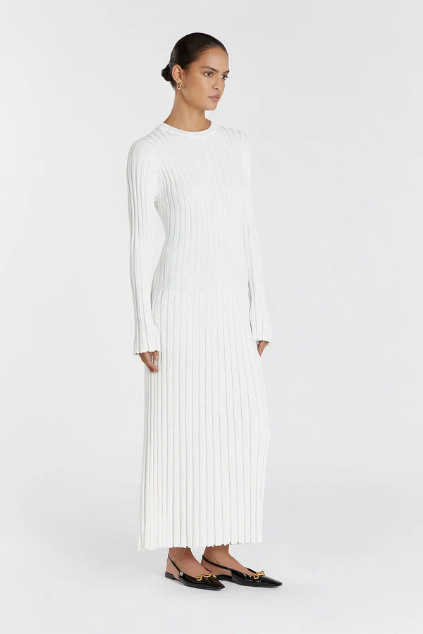 Woman wearing a long white ribbed dress on a white background
