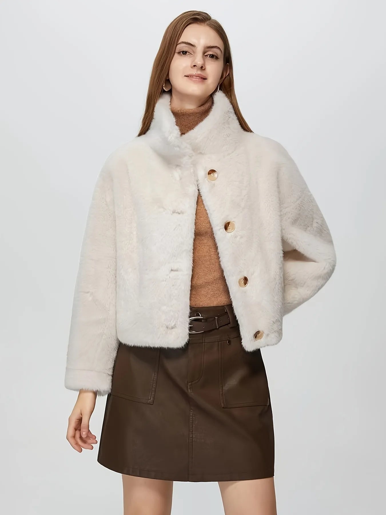 Woman wearing a cream-colored coat with fur trim on a white background