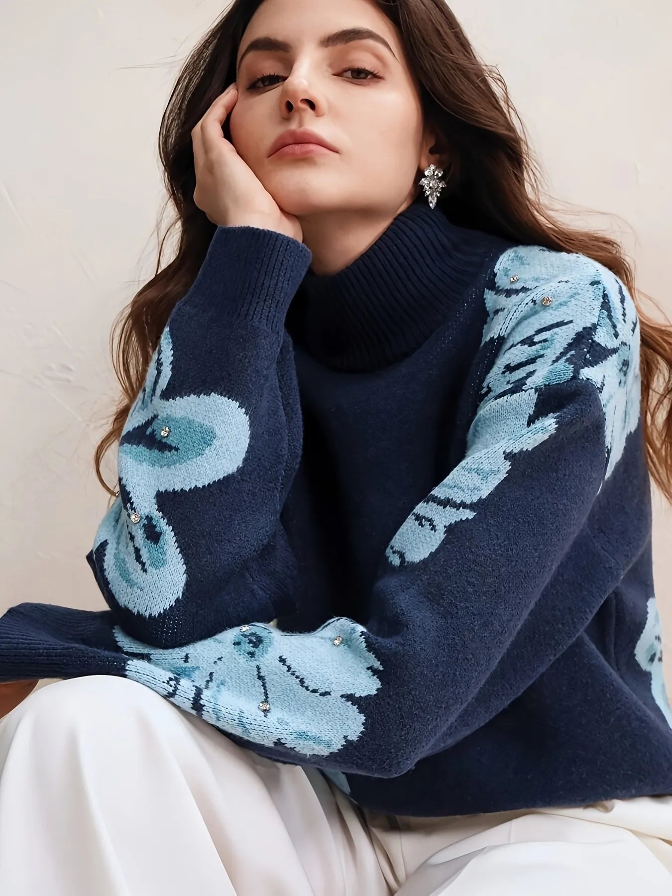 Woman wearing a navy sweater with blue butterfly patterns on a neutral background