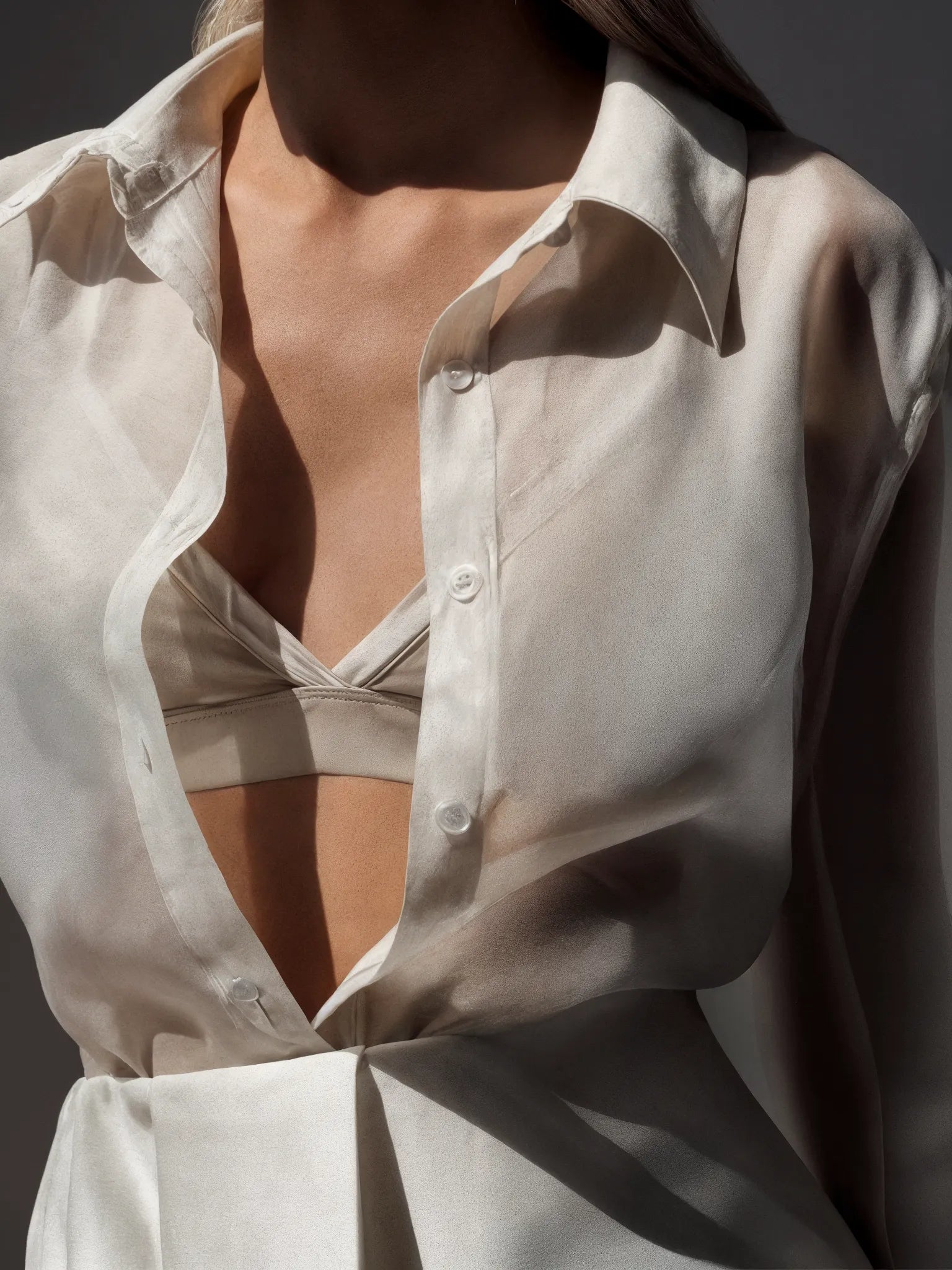 Close-up of a person wearing an open white shirt against a dark background