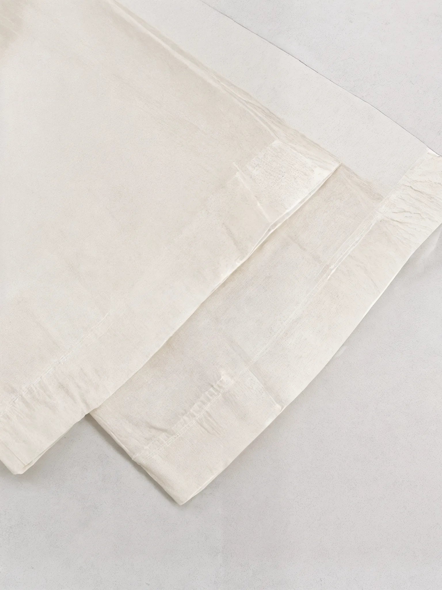 Two beige folded towels on a light gray background