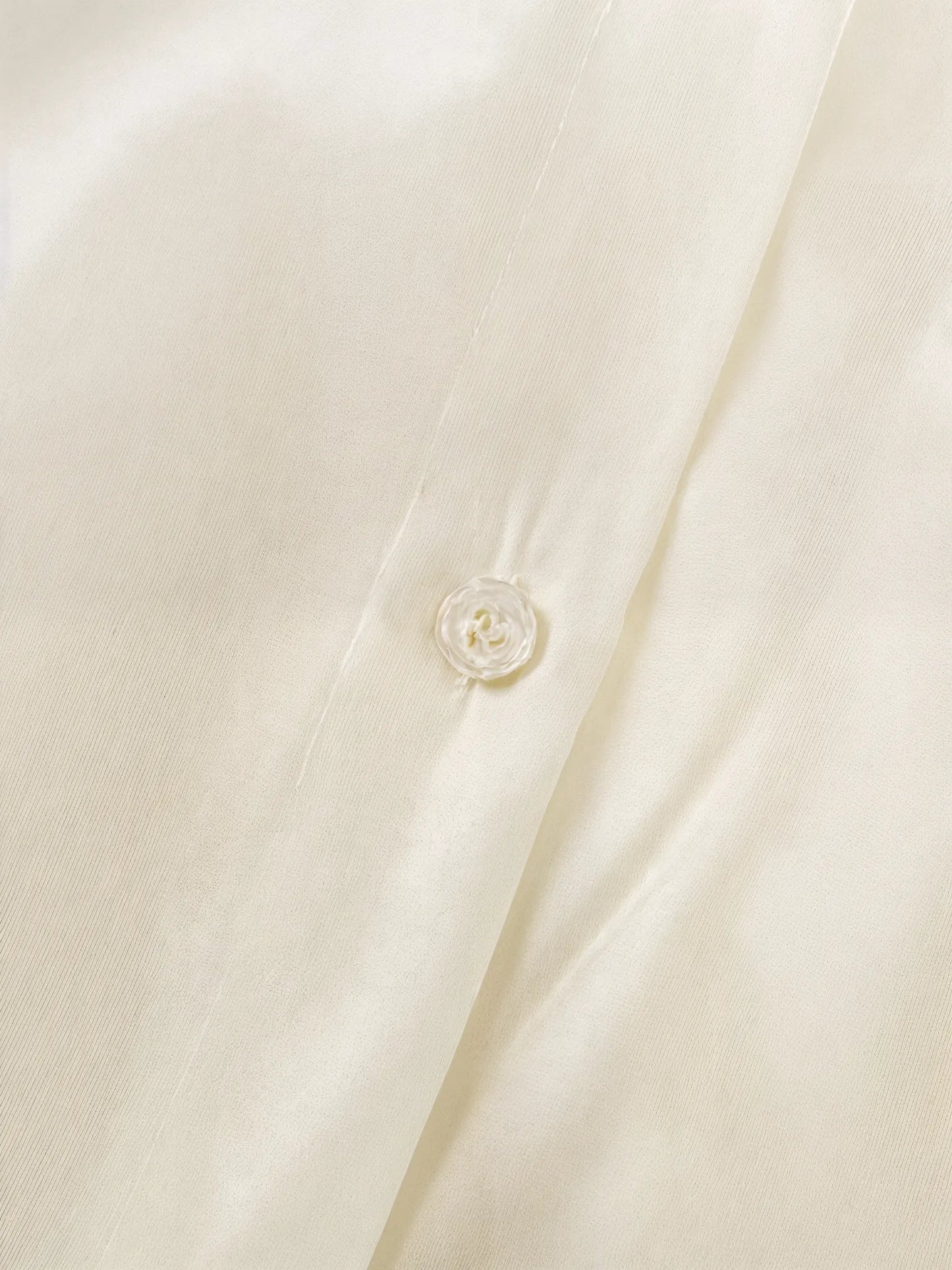 Close-up of a beige buttoned shirt with a button detail.