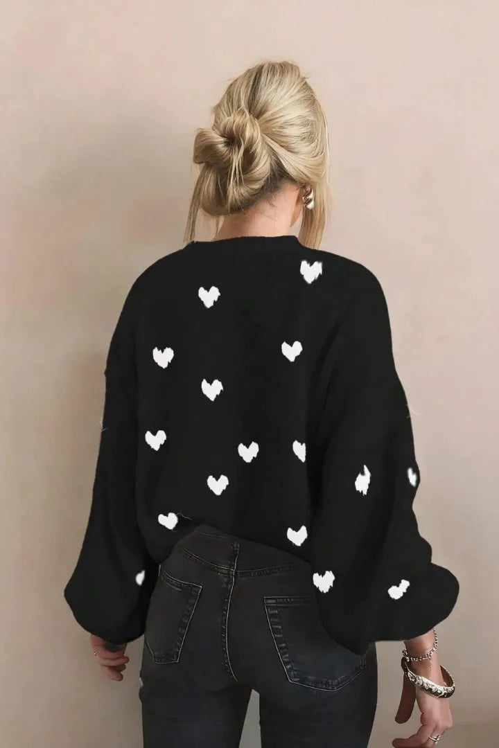 Person wearing a black sweater with white heart patterns on a beige background