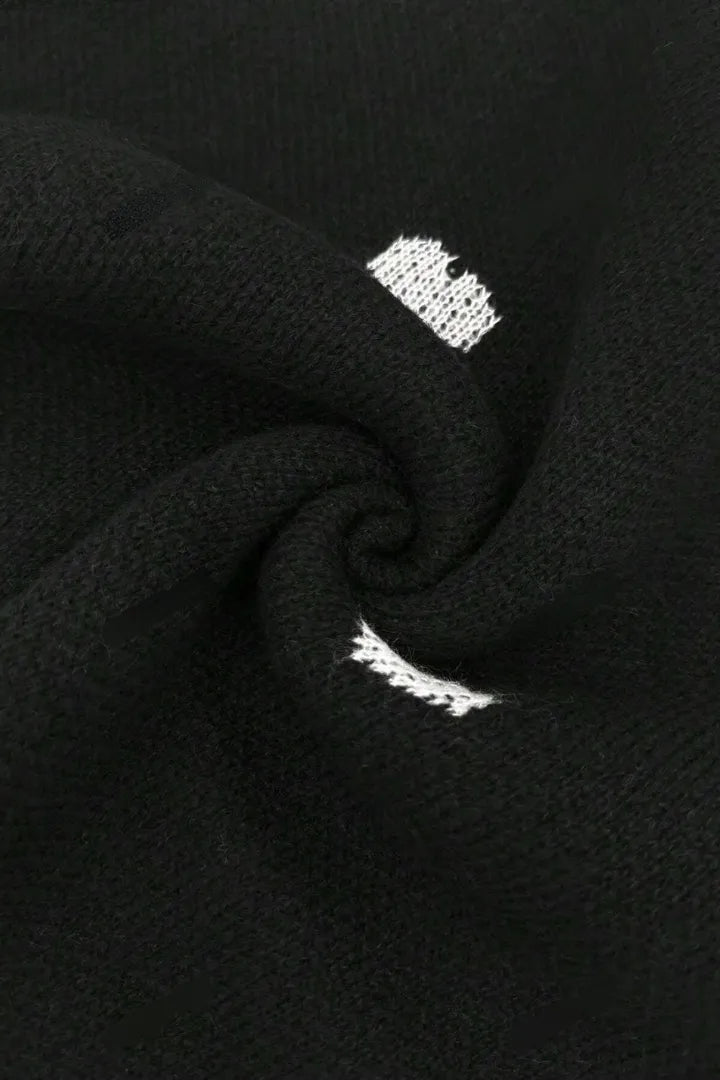 Close-up of black fabric with white embroidered designs.