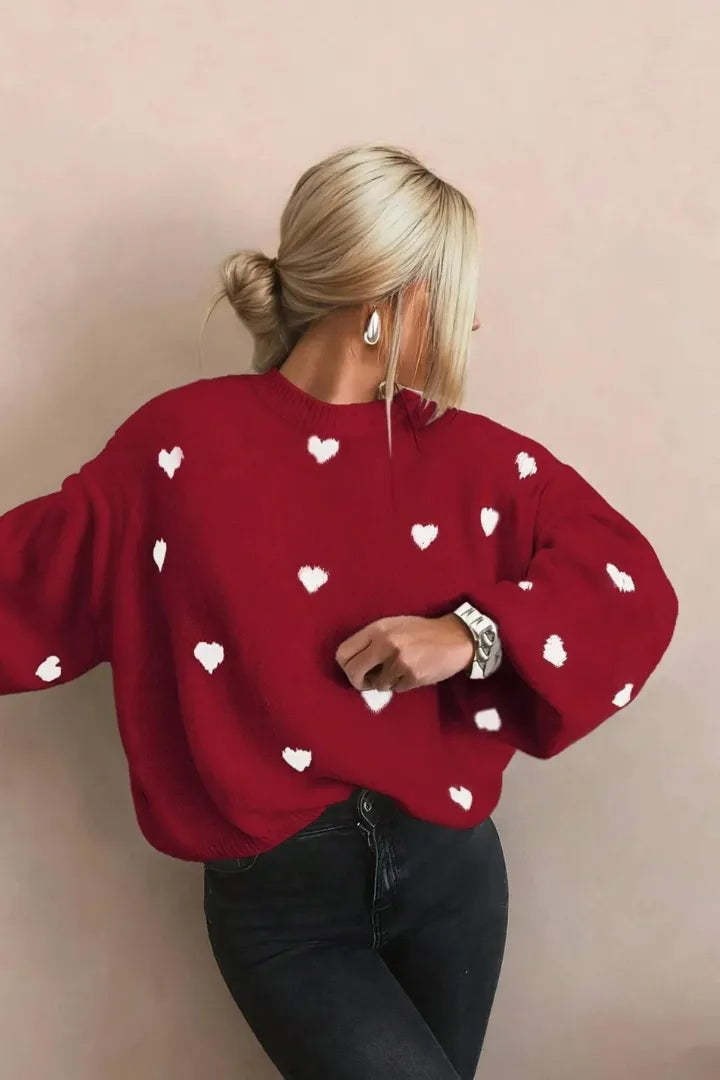 Person wearing a red sweater with white heart patterns against a beige background