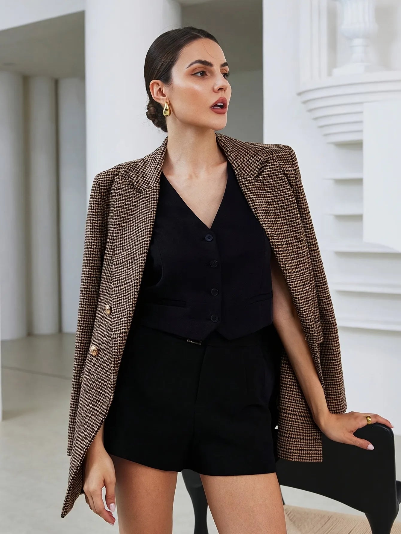 Woman wearing a brown blazer over a black outfit in an indoor setting