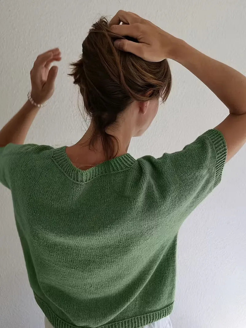Person wearing a green sweater against a plain background