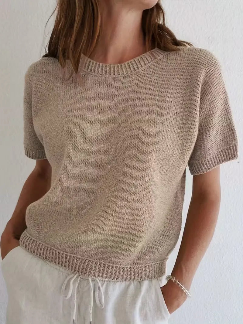 Person wearing a beige knitted sweater against a white background