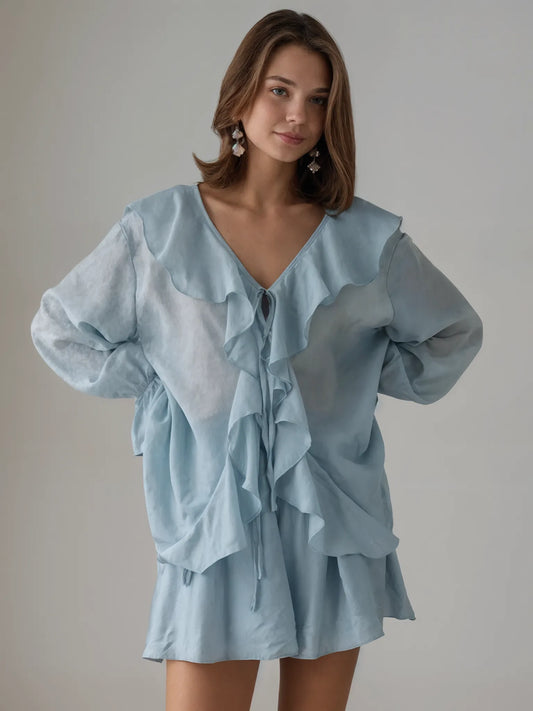 Woman wearing a light blue dress with ruffled layers against a plain background