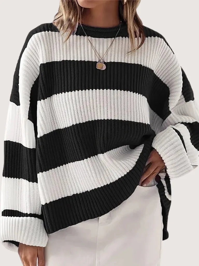 Person wearing a black and white striped sweater on a plain background