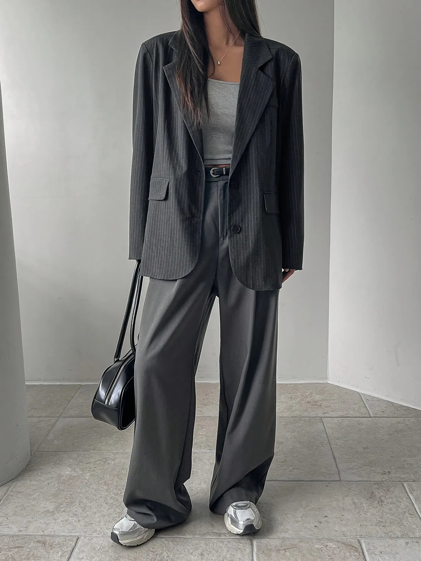 Person wearing a dark gray suit with a plain background