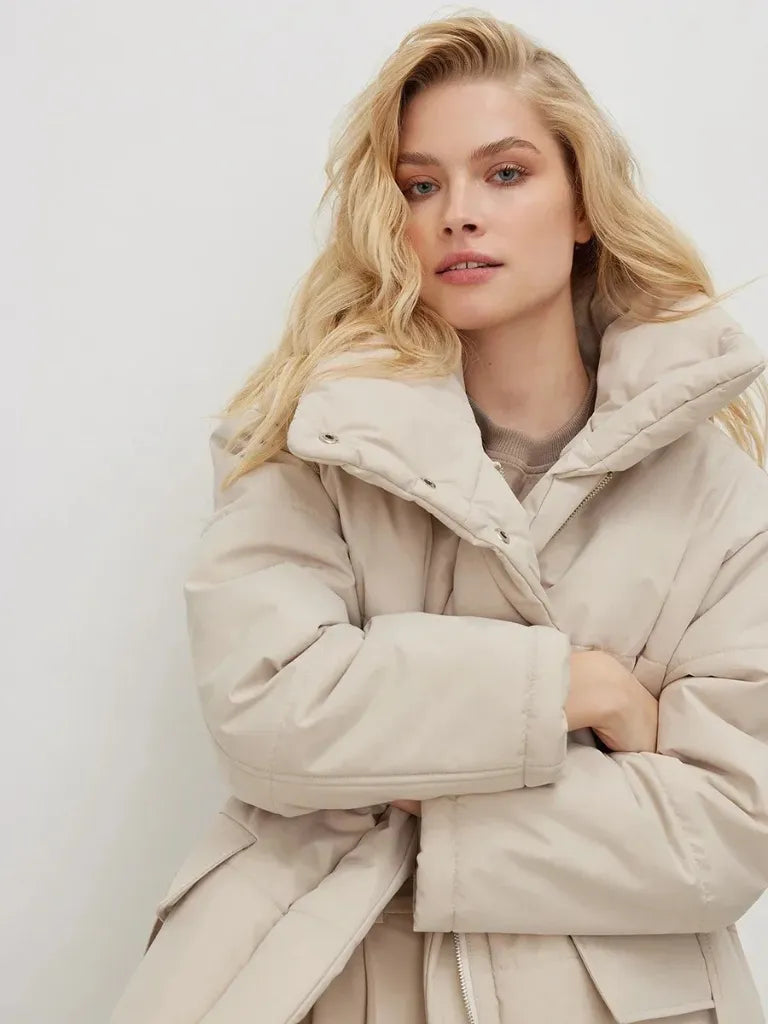 Woman wearing a beige puffer coat against a white background
