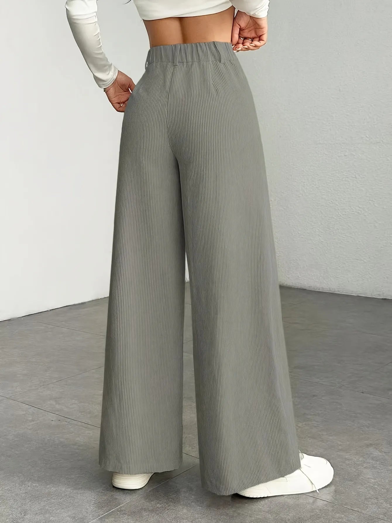 Person wearing gray wide-leg pants on a plain background