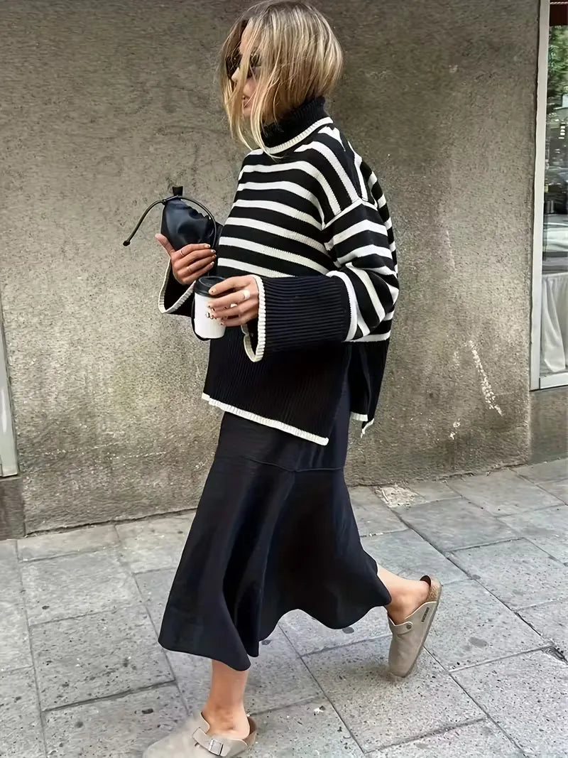 Person wearing a black and white striped sweater and black skirt on a city street.