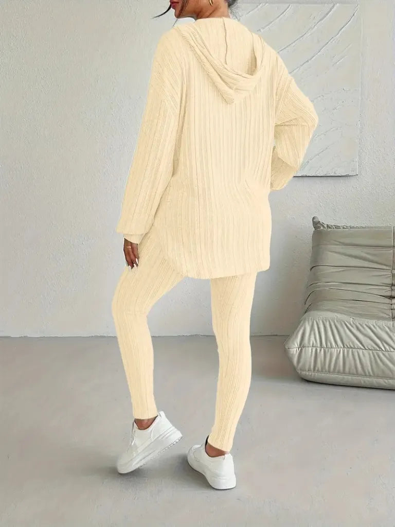 Person wearing a beige knit outfit in a minimalistic room.