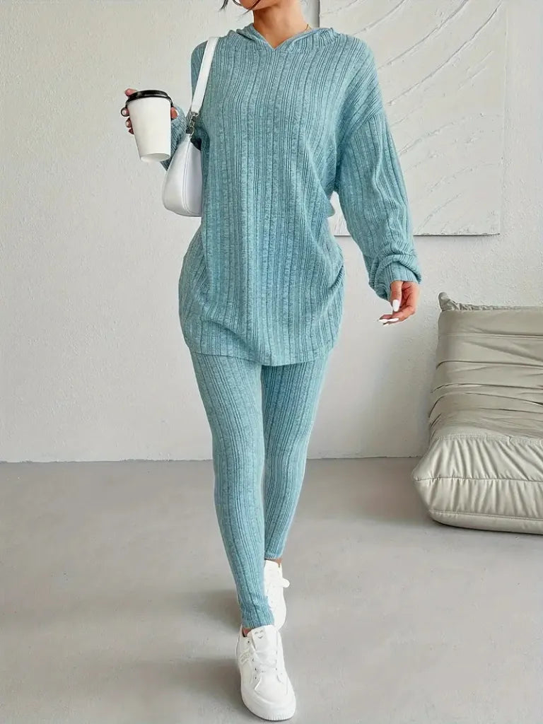 Person wearing a teal ribbed loungewear set holding a white mug indoors.
