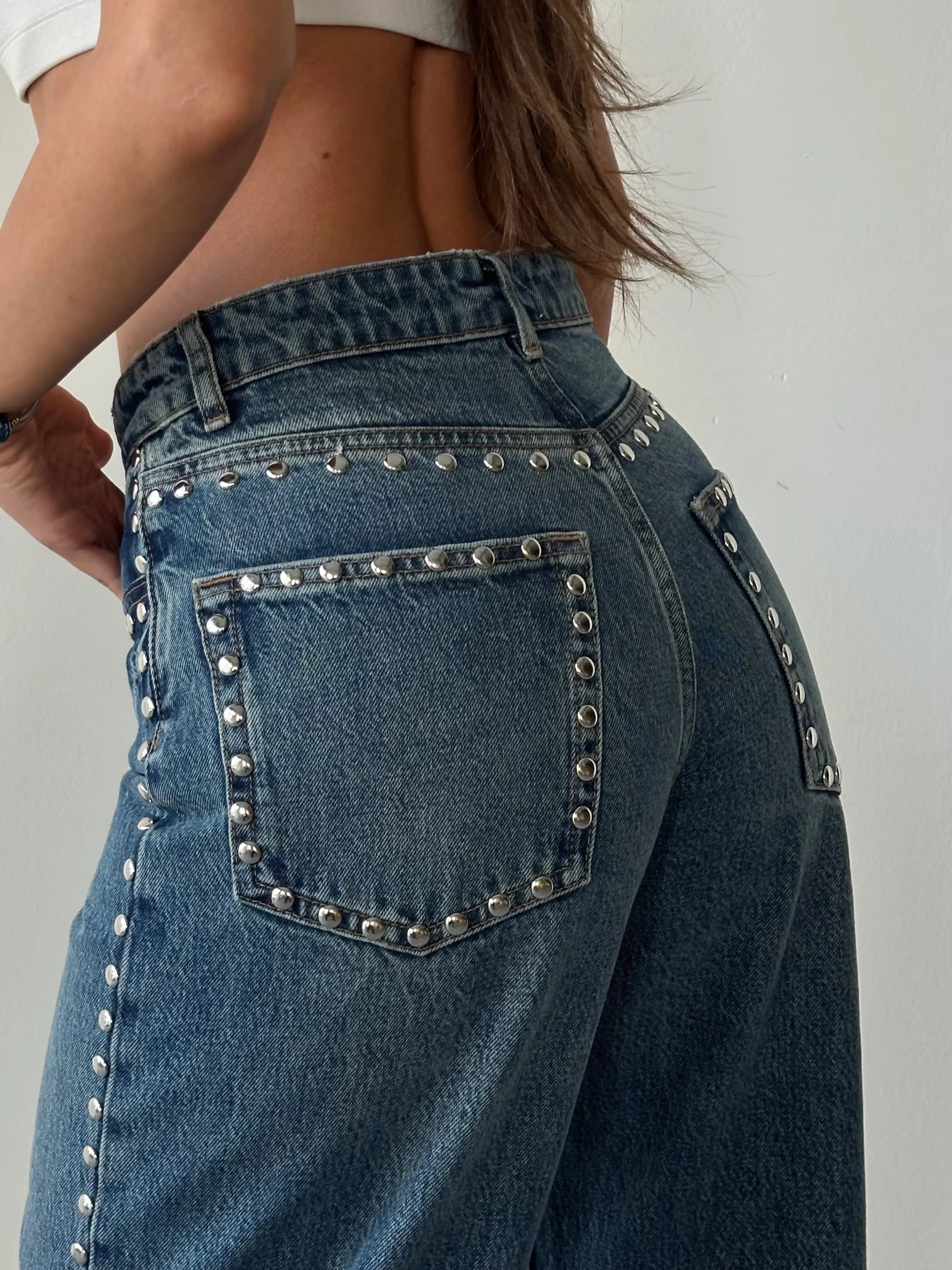 Blue jeans with studded details on a plain background
