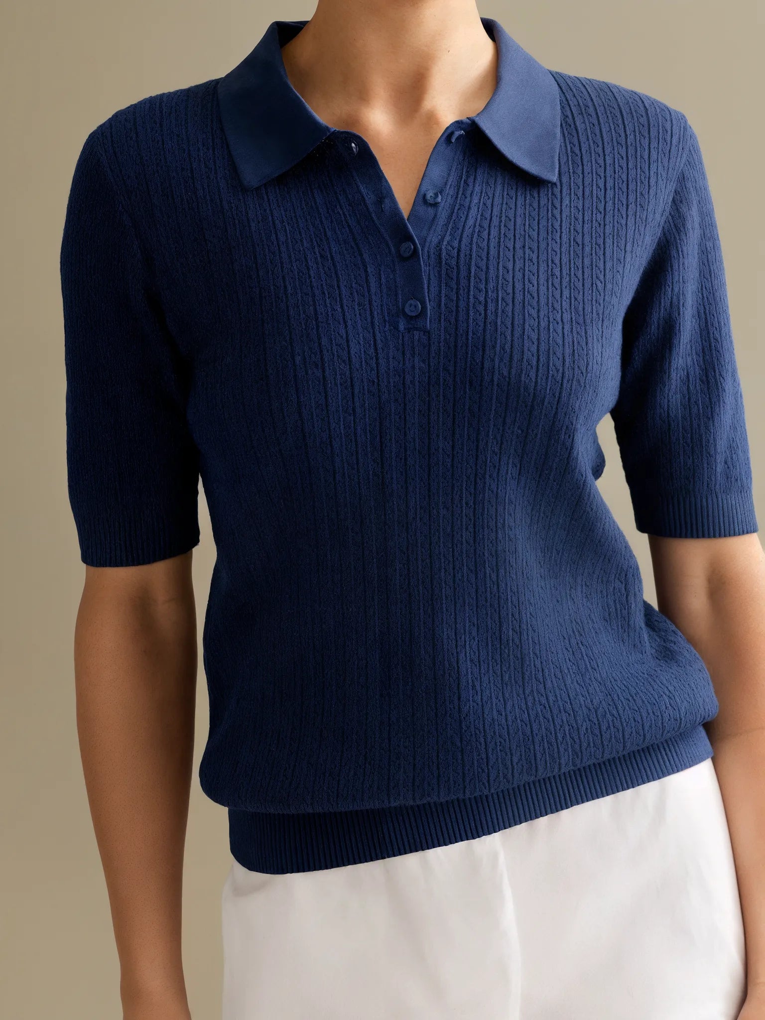 Navy blue ribbed sweater with short sleeves on a neutral background