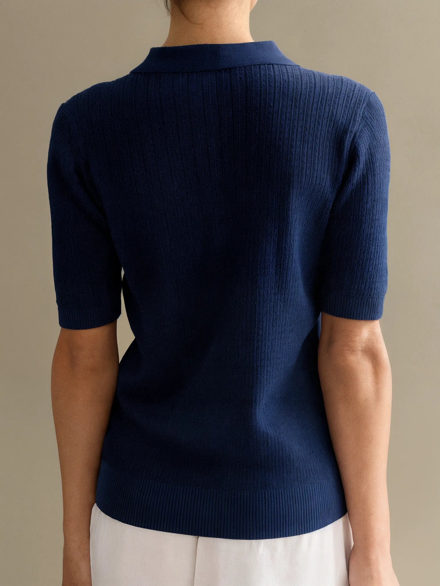 Navy blue short-sleeve sweater worn by a person on a beige background