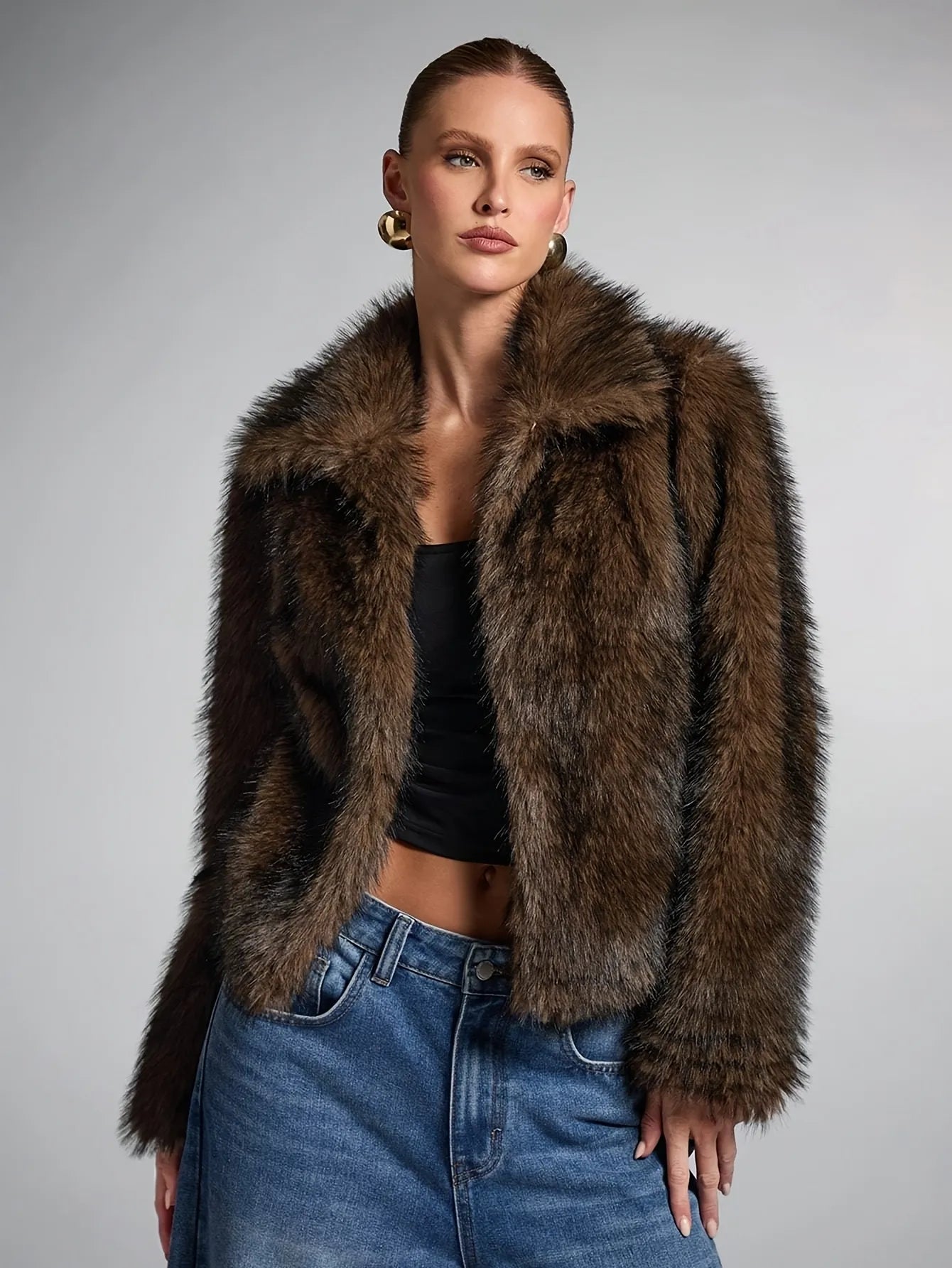 Woman wearing a brown fur jacket and blue jeans against a gray background