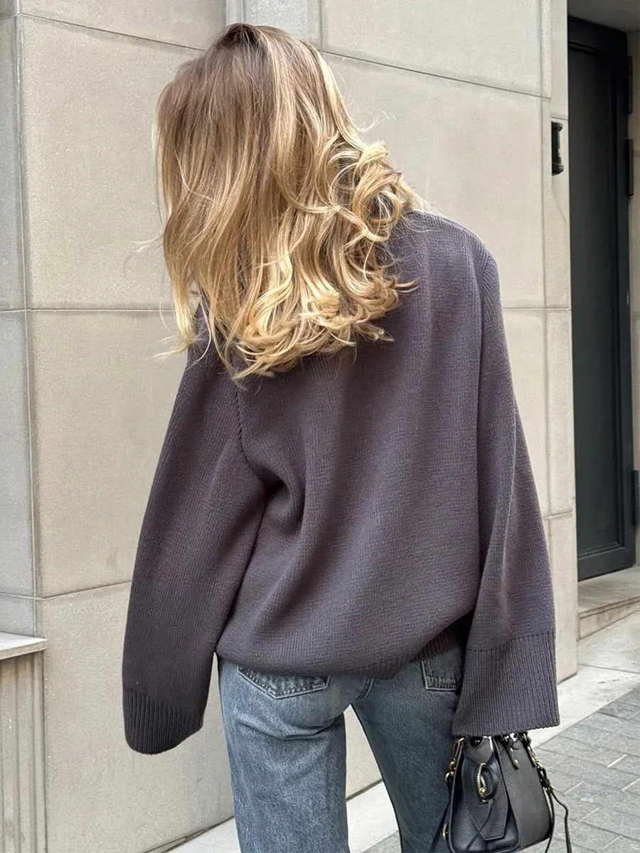 Person wearing a gray sweater and blue jeans walking away from the camera.