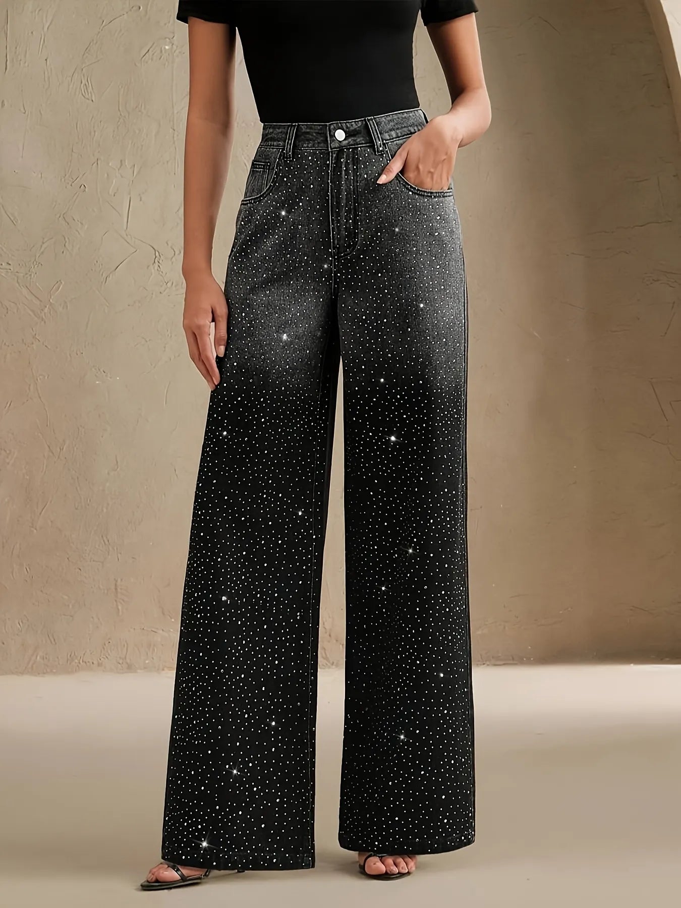 Person wearing black wide-leg jeans with star patterns on a beige background