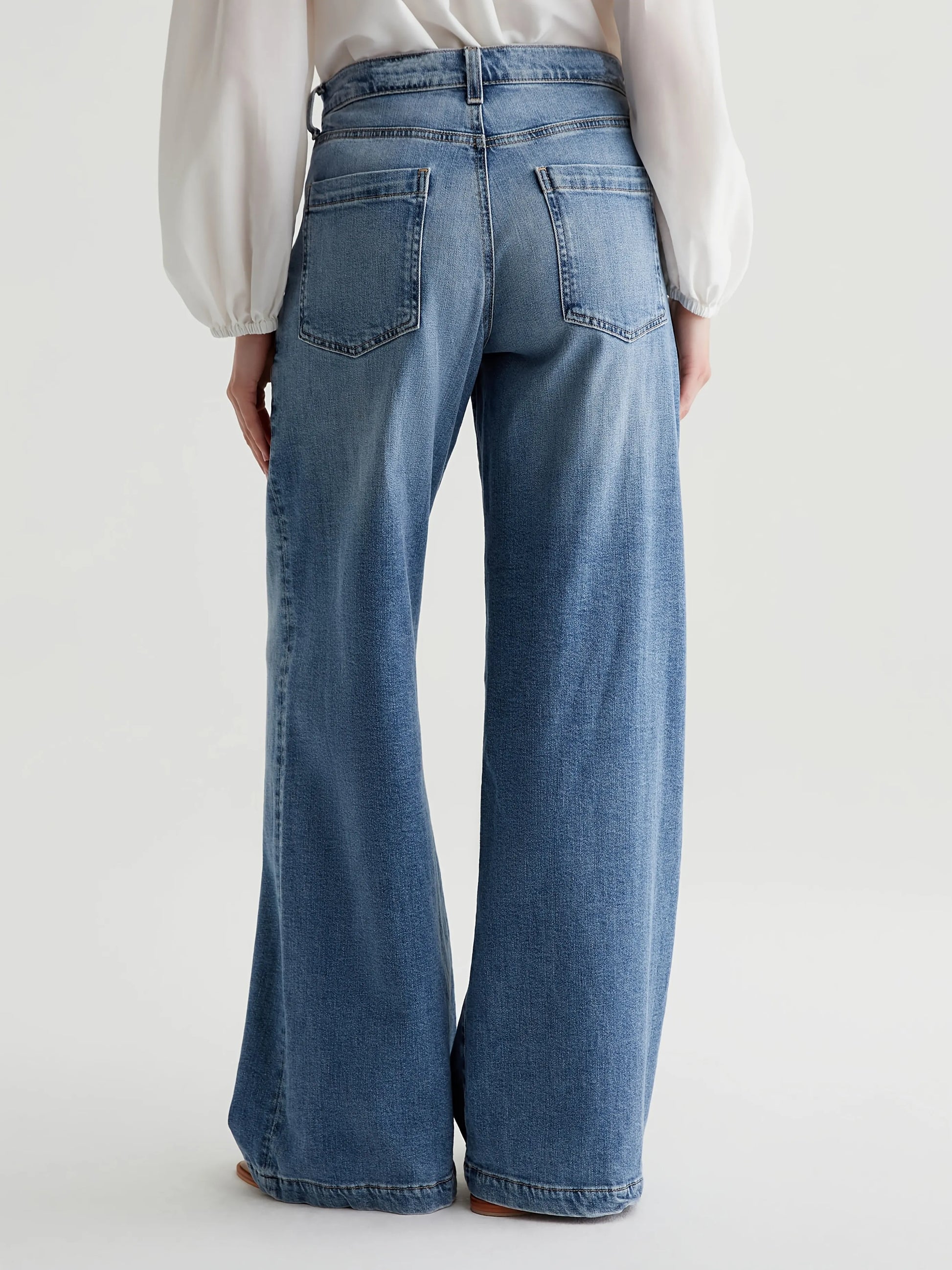 Person wearing blue jeans on a plain background