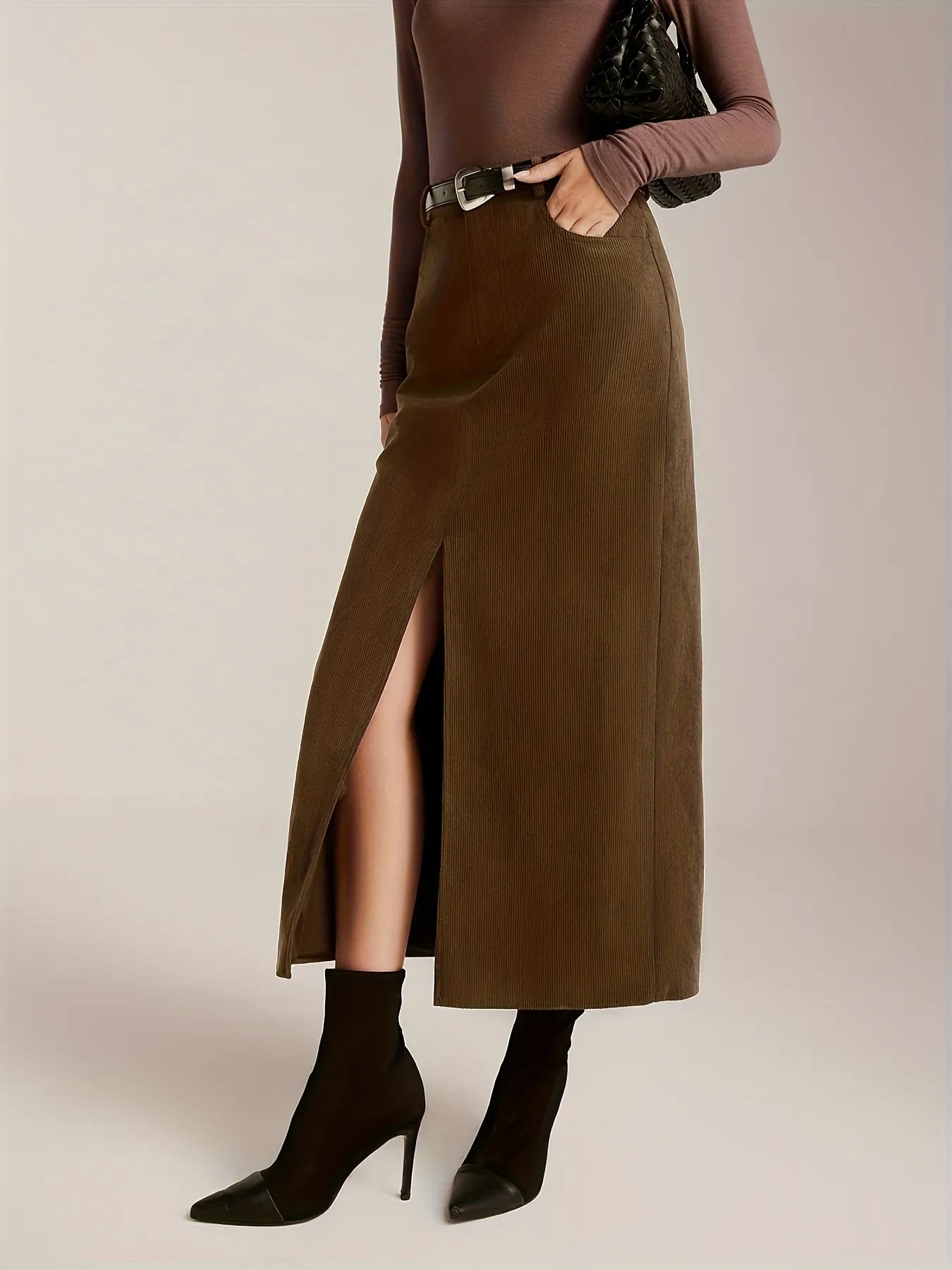 Person wearing a brown long skirt with a high slit on a plain background