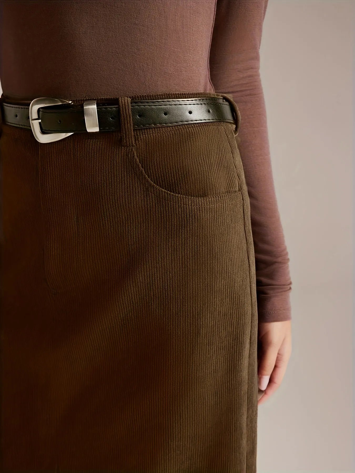Person wearing a brown corduroy skirt and brown top with a belt.