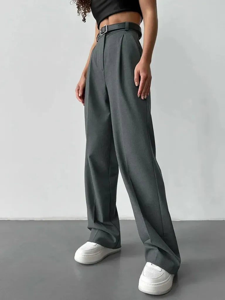 Person wearing dark green wide-leg pants with a plain background