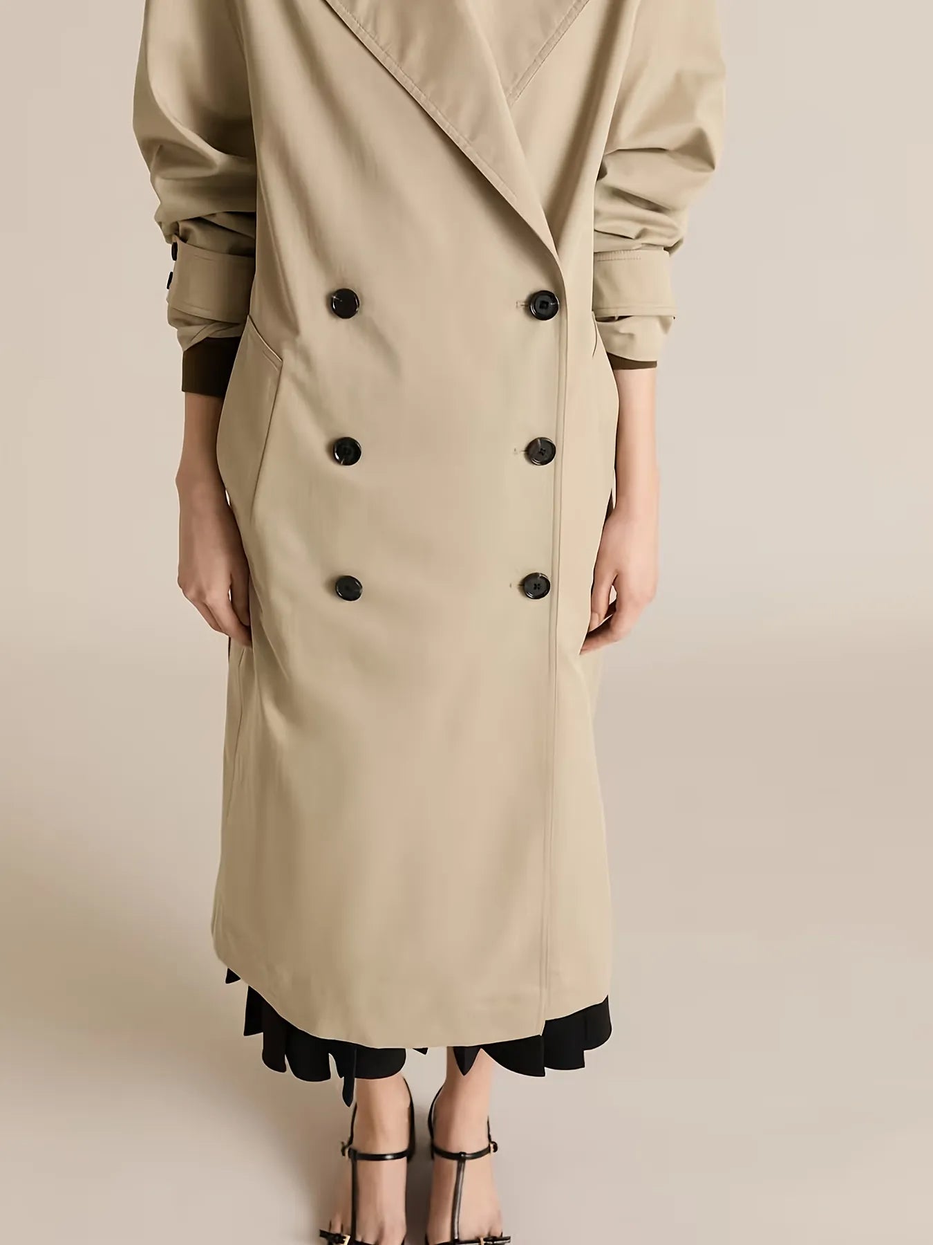Beige trench coat with black buttons on a beige background