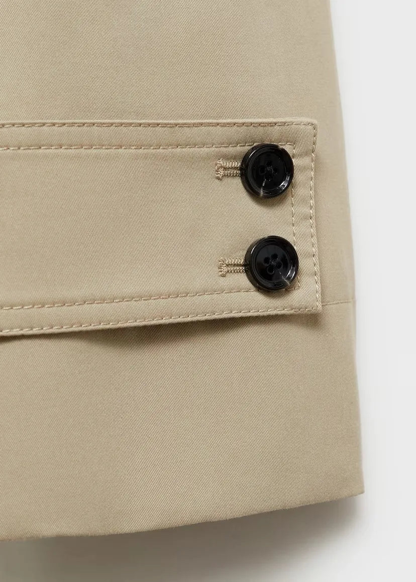 Close-up of beige pants with black buttons on a white background