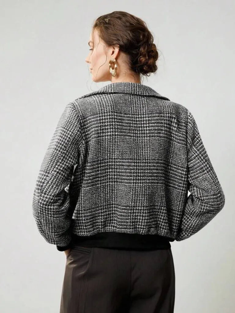 Person wearing a black and white checkered jacket on a plain background