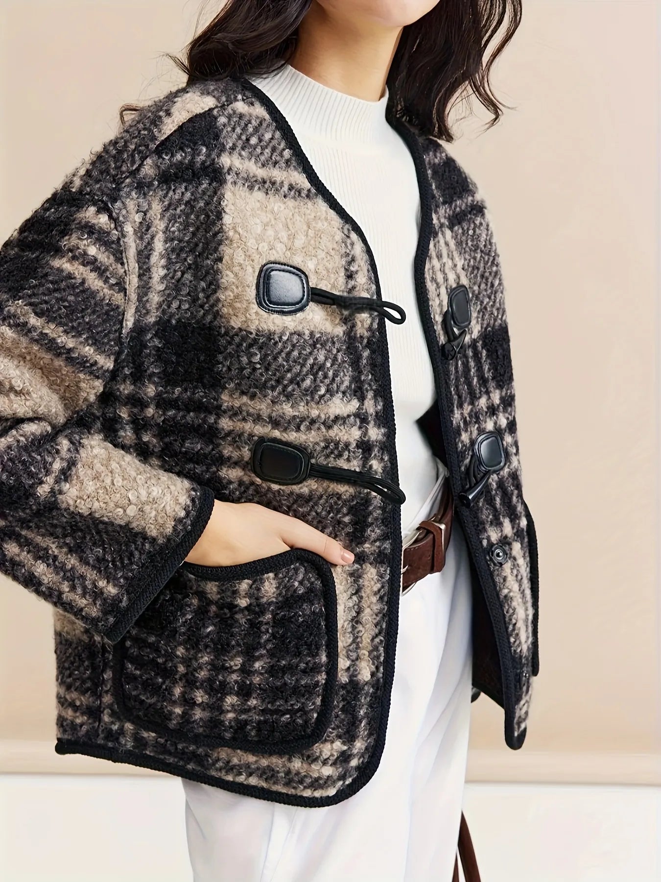 Woman wearing a plaid jacket with a plain background