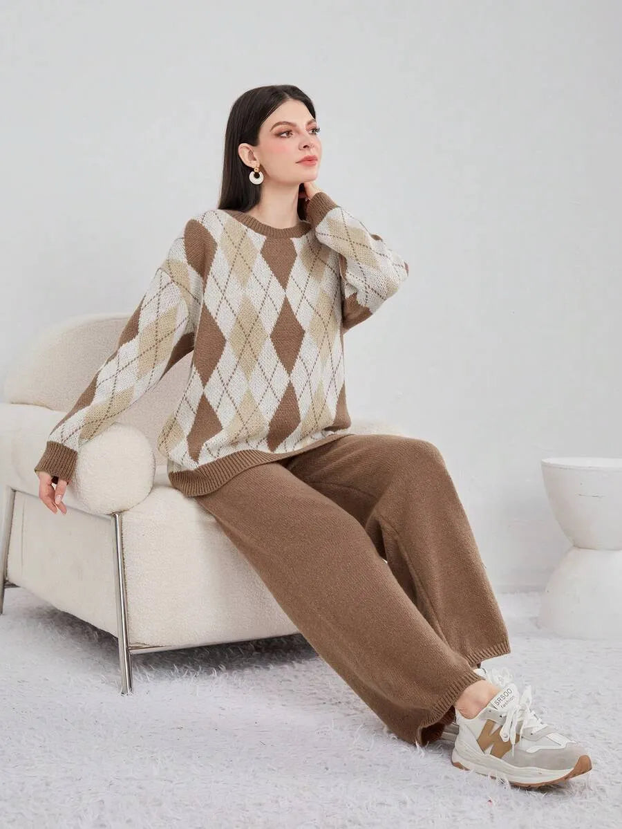 Woman wearing a brown and beige argyle sweater and pants sitting on a white chair.