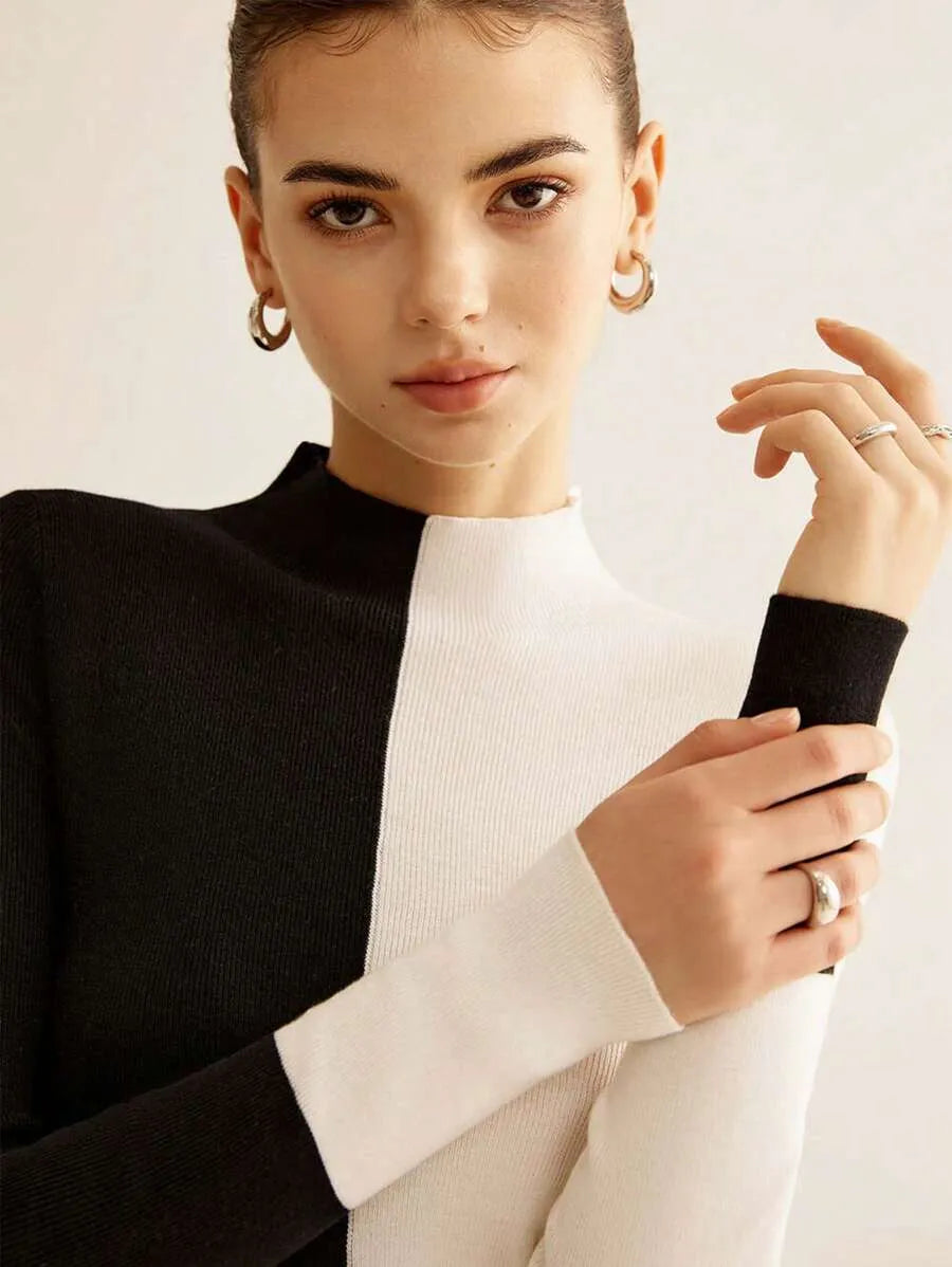 Woman wearing a black and white outfit with jewelry on a plain background