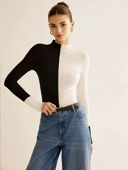 Woman wearing a black and white long-sleeve top with blue jeans on a plain background