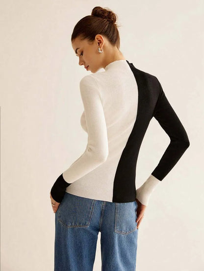 Woman wearing a black and white long-sleeve top with a neutral background
