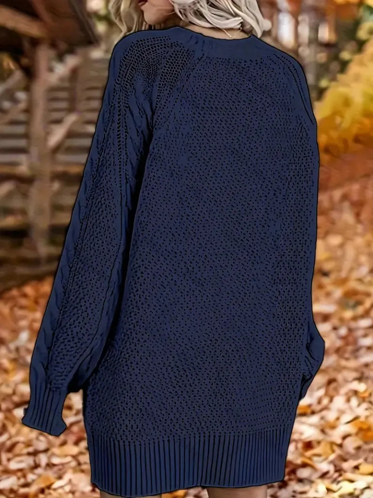 Navy blue knitted sweater worn by a person with a blurred autumn background