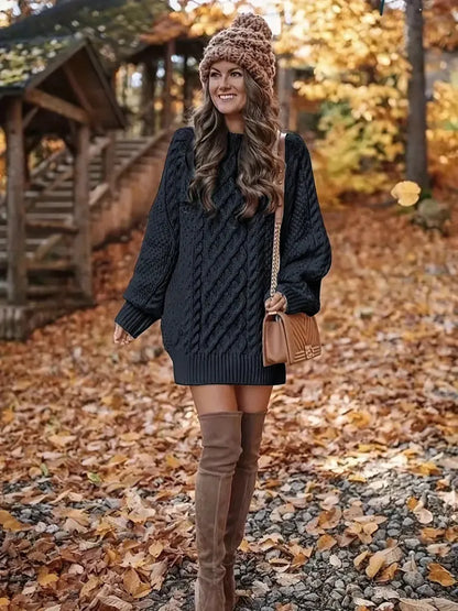 Woman in a dark sweater dress and brown knee-high boots standing in autumn leaves.