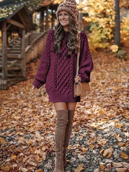 Woman in a purple sweater and brown over-the-knee boots standing in an autumn setting.