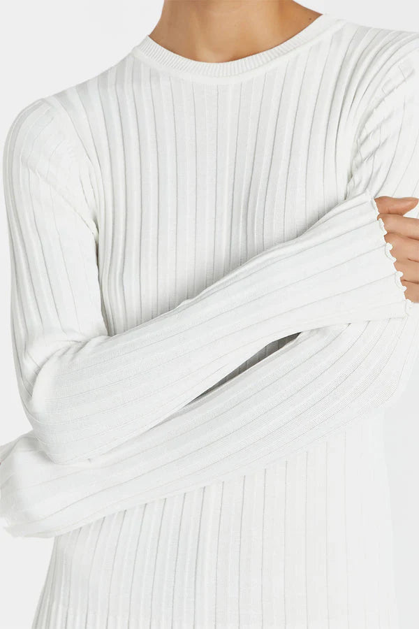 Close-up of a person wearing a white ribbed sweater.