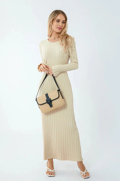 Woman wearing a beige ribbed dress holding a beige handbag on a white background