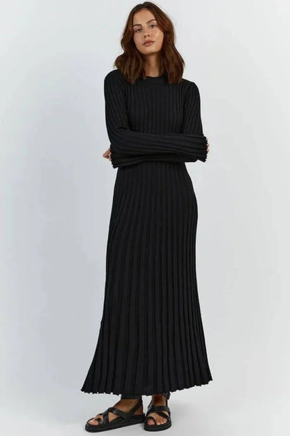 Woman wearing a black pleated dress against a white background