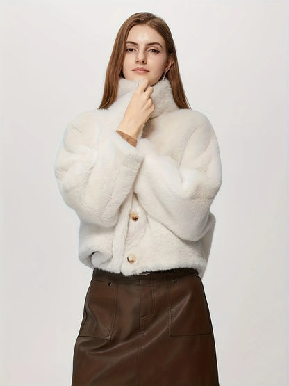 Woman wearing a white textured sweater with brown leather skirt on a light background